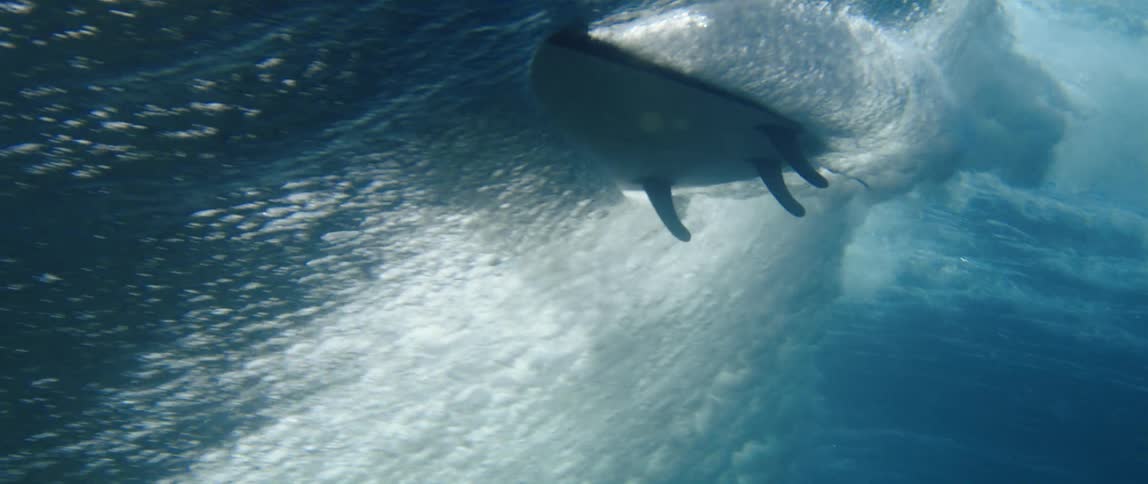 Surfboard rides a wave seen from underwater