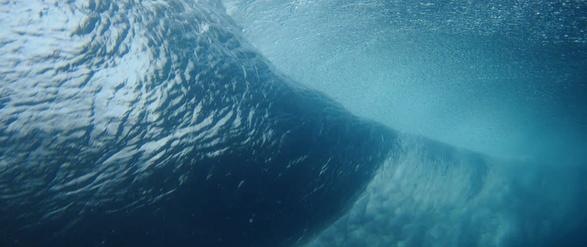 From below the ocean surface a large wave is seen passing overhead