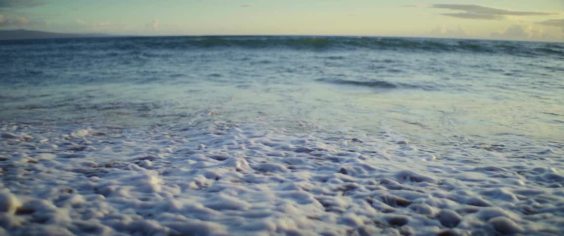 Waves splash and curl as they roll into shore and over the beach