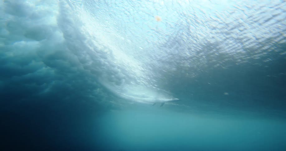 A surfer is captured riding a breaking wave from an underwater view