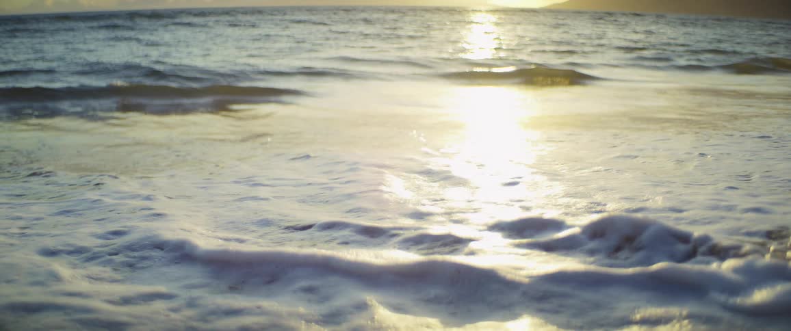 Small waves crash ashore a beach in the evening