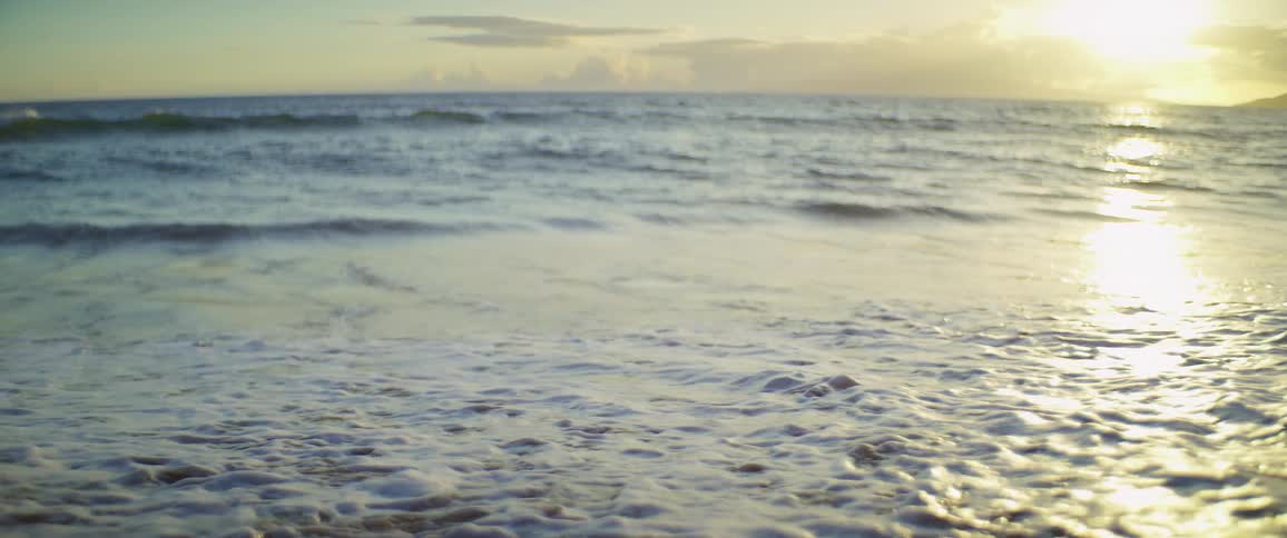 The wave crashes on the beach on a sunny day