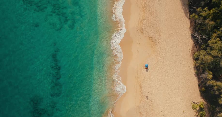 Aerial view of a beach next to turquoise ocean waves