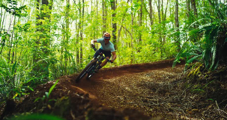 The man rides his bike down the trail in the forest