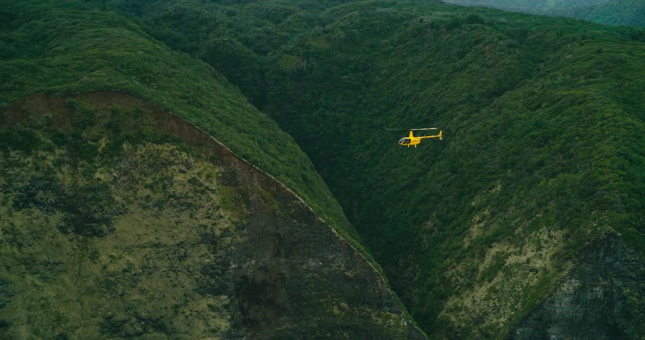 A helicopter flies over a hill and valley