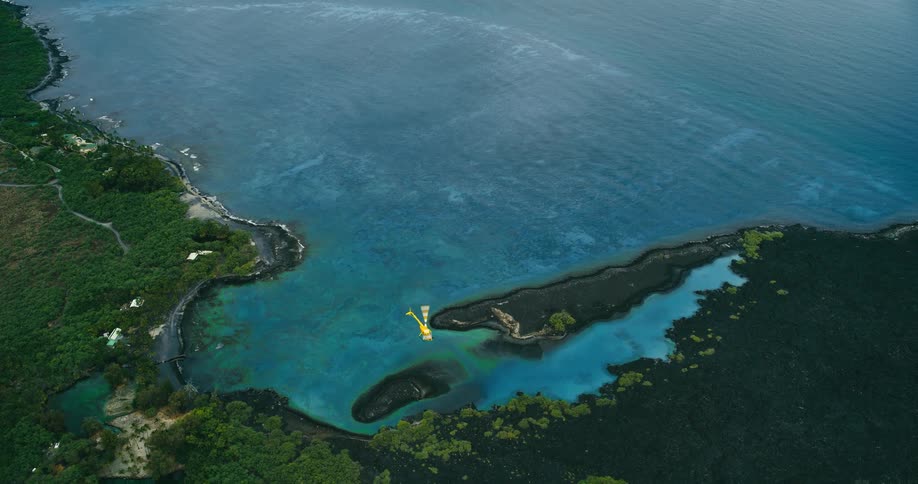 A high aerial shot reveals a yellow helicopter flying over a stunning volcanic coastline with turquoise bays and black rock