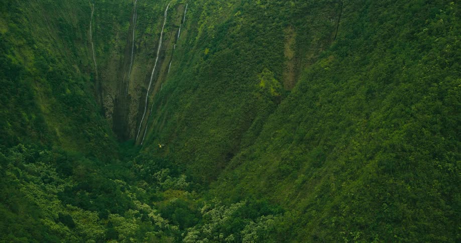 Aerial view of a green valley with waterfalls flowing down the mountain slopes