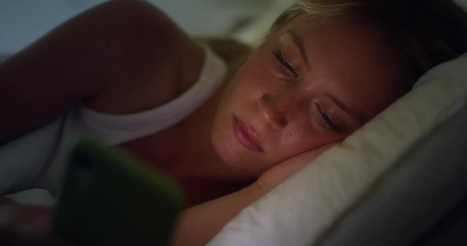 Woman lying in bed looking at her phone