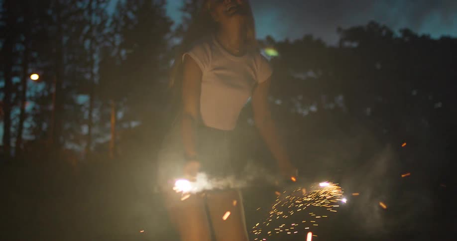 The woman runs at night with two sparklers in her hands