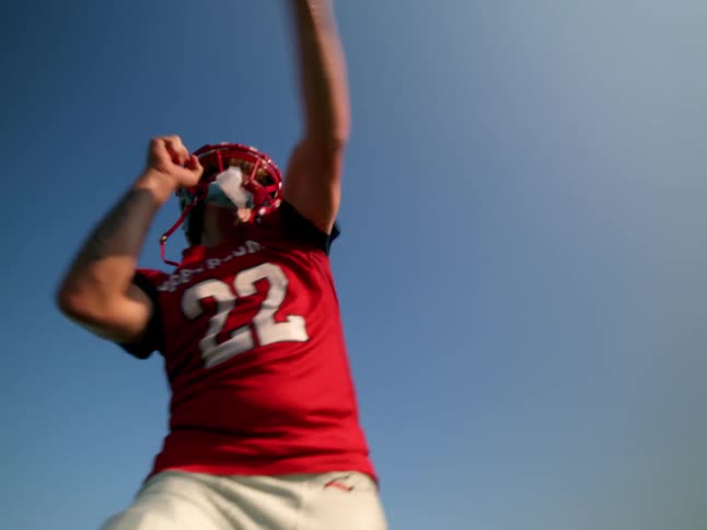 Teenage quarterback in red jersey throwing a football