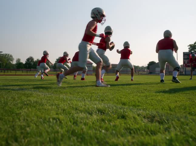 A high school football team practices running an offensive play