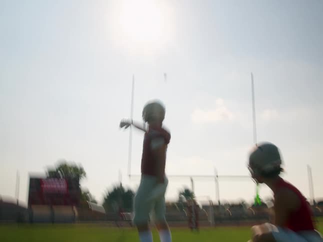 American football players on the field with one athlete kicking the ball while another holds it in place for the play