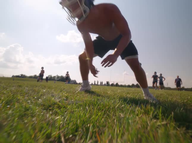 A man wearing a helmet hikes a football to a group of men