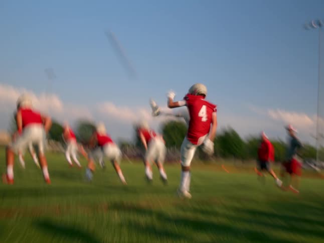 The video shows a team of football players practicing on a green field the players are wearing red and white jerseys and they are shown running and moving the ball down the field during the play