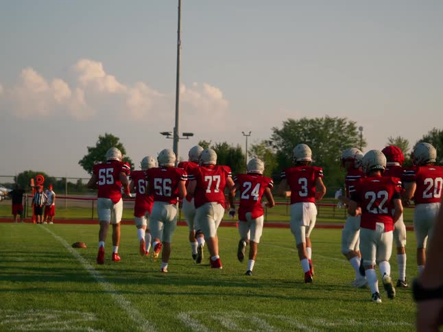 Football players in red uniforms run onto the field together