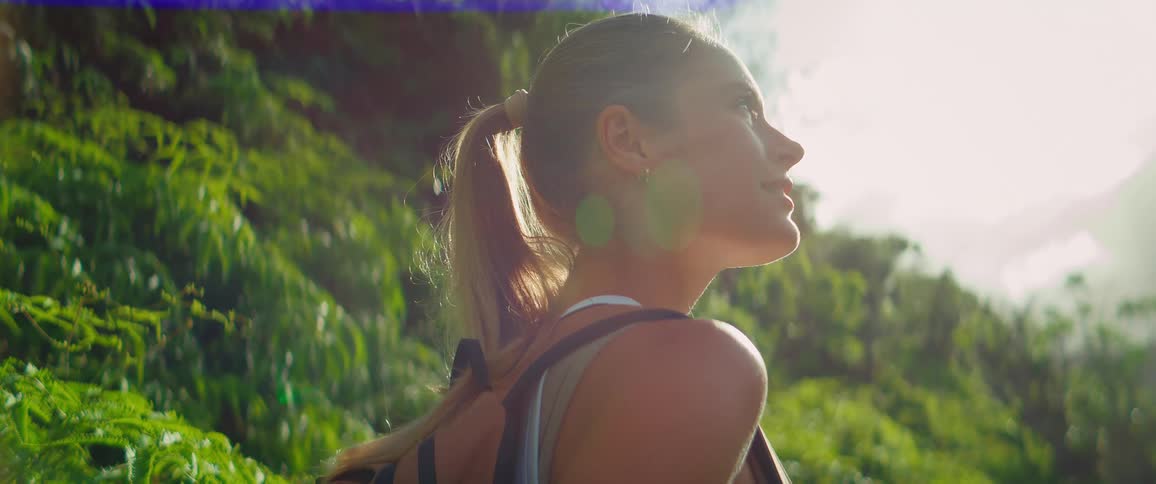 A woman with a backpack hikes through a tropical forest