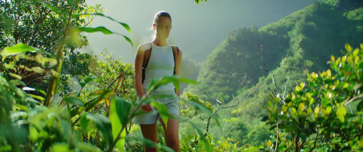 The woman hikes through the green hills
