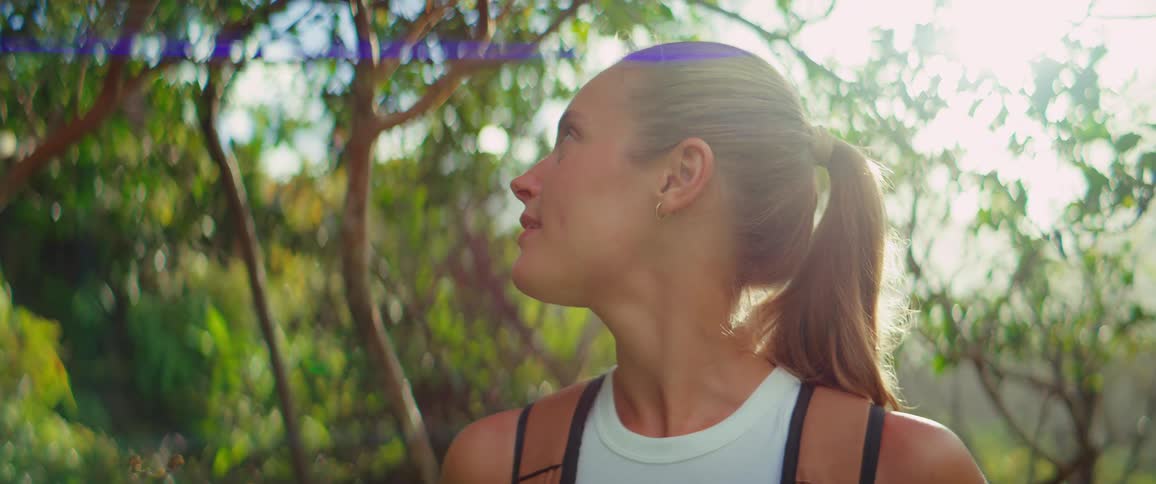 A woman smiles as she looks around at her surrounds while outdoors