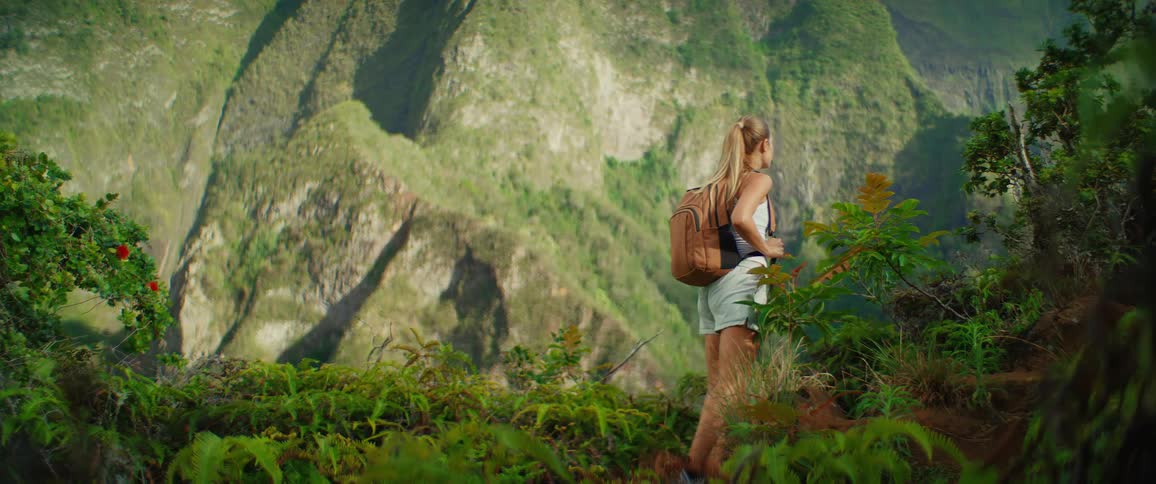 The woman hiking on the mountain climbs up a hill