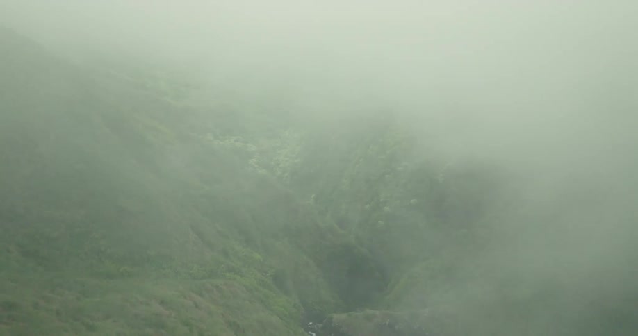 An aerial view of a misty canyon with a narrow river