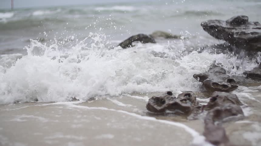 Waves rolling and crashing against rocks and the sandy shore