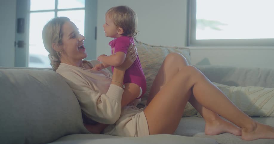 Mother lying on the couch receives a loving kiss from her little daughter