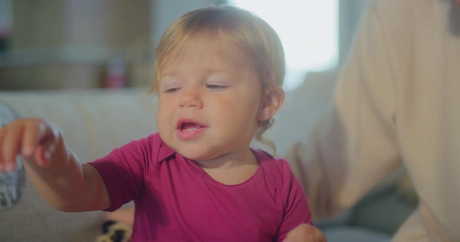 A toddler smiles and plays on the couch at home