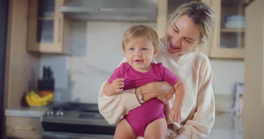 The mother smiles while holding her baby