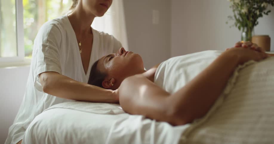 One woman gently massages the shoulders and neck of another woman