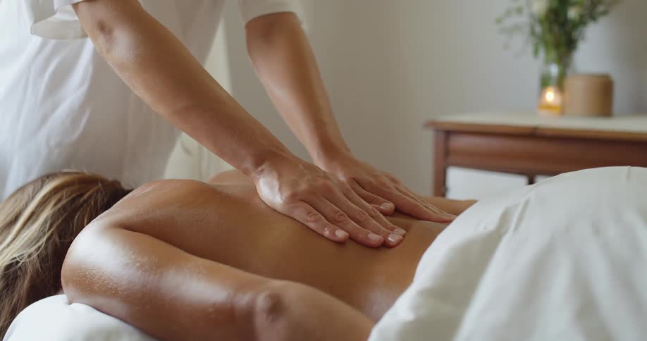 Close up of a young woman receiving a back massage from a masseuse at a spa