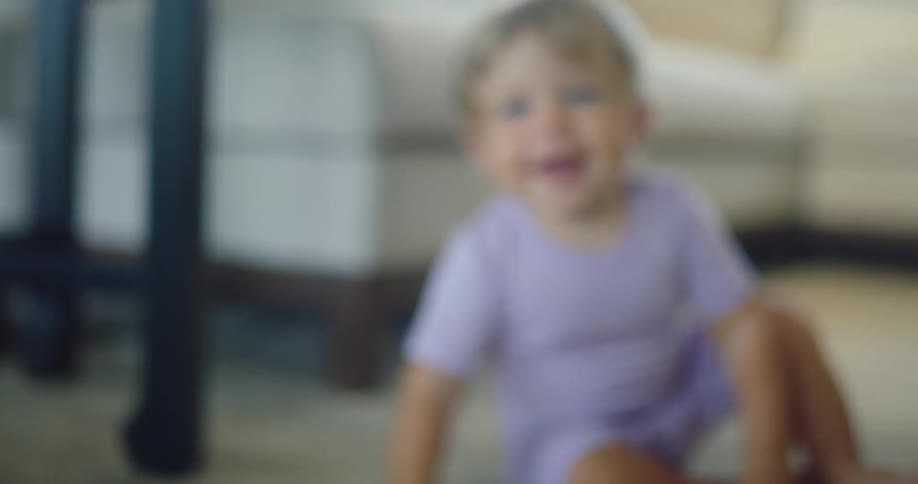 Baby in lilac clothes crawling on a carpet indoors