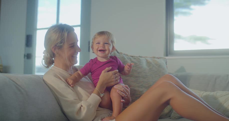 A mother holds her daughter and they are laughing on the couch