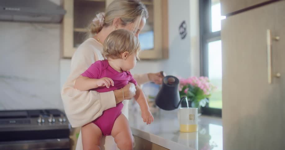 A mother pours water while holding her baby