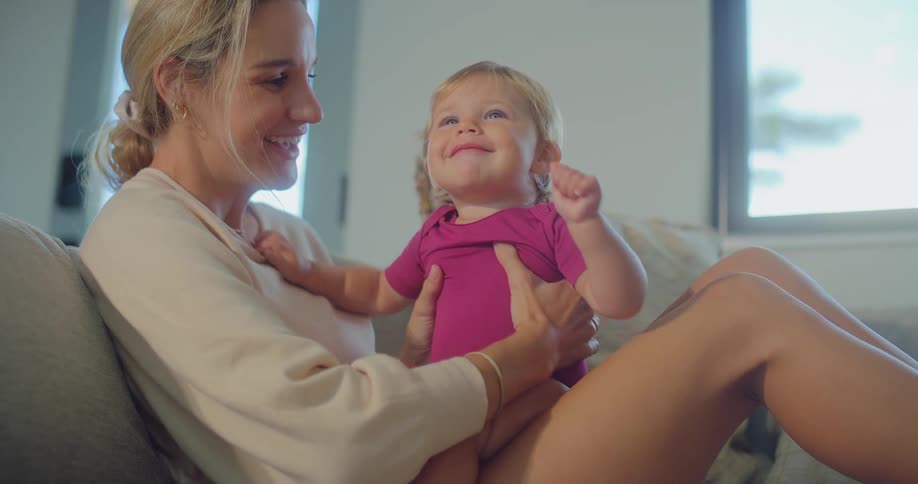 A mother lifts her baby up and gives her a kiss
