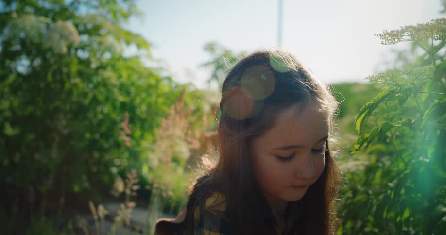 Girl picking flowers in the garden on a sunny autumn day puts them in a basket