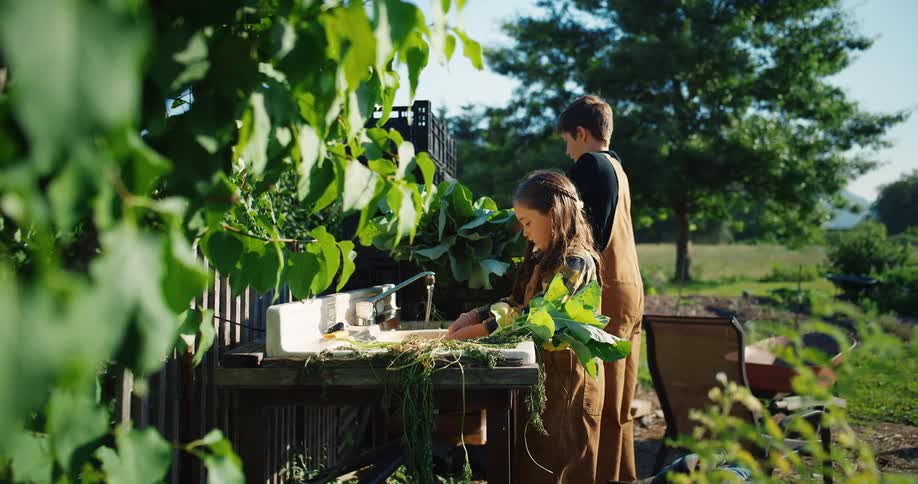 Children in overalls tend plants at an outdoor garden station