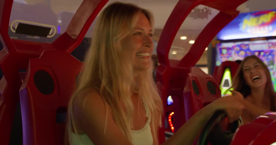 Two women in an arcade having fun and excited while playing a car game