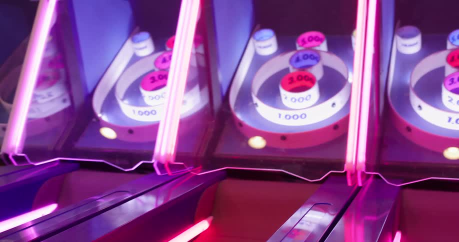 A woman throws a skee ball into the hole at an arcade