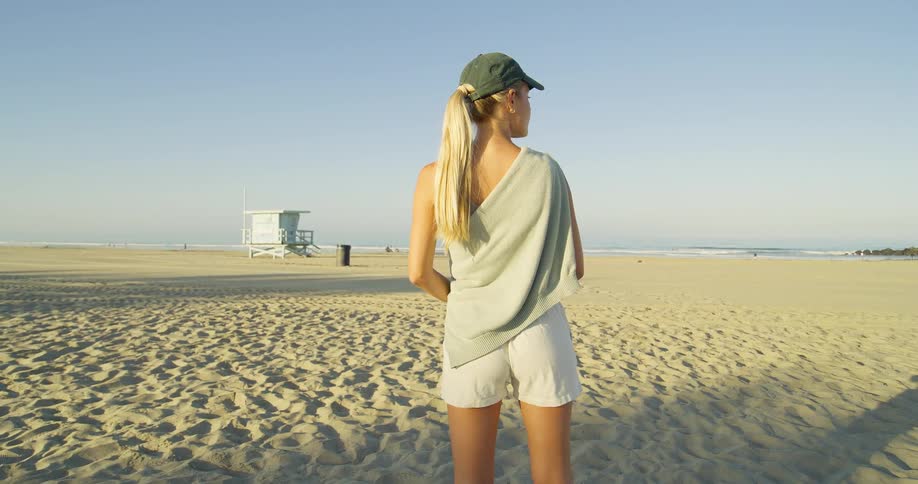 A woman stands on the beach overlooking the ocean