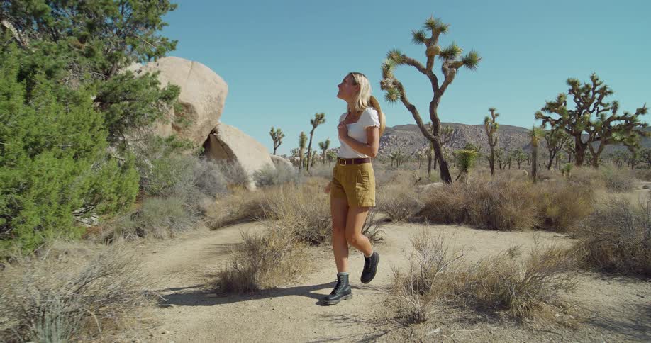 The woman smiles and hikes in the sand