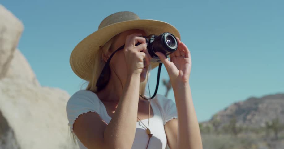 A woman photographer lifts her camera to frame the desert scenery