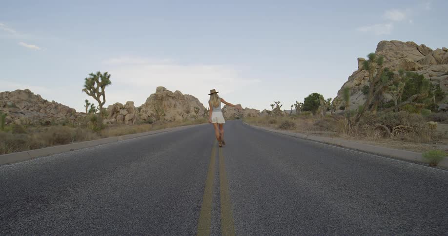 The woman balances on the yellow line on the road
