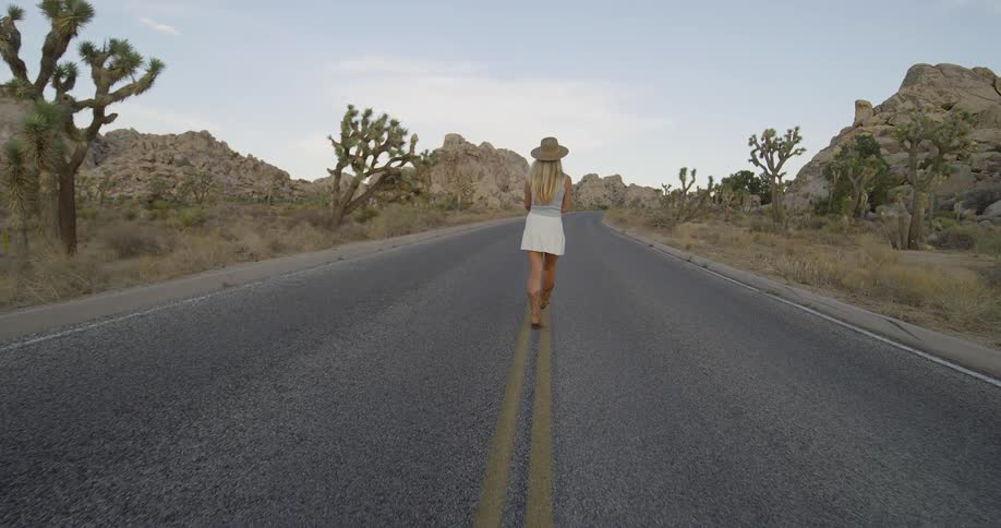 The woman is hiking on the empty road