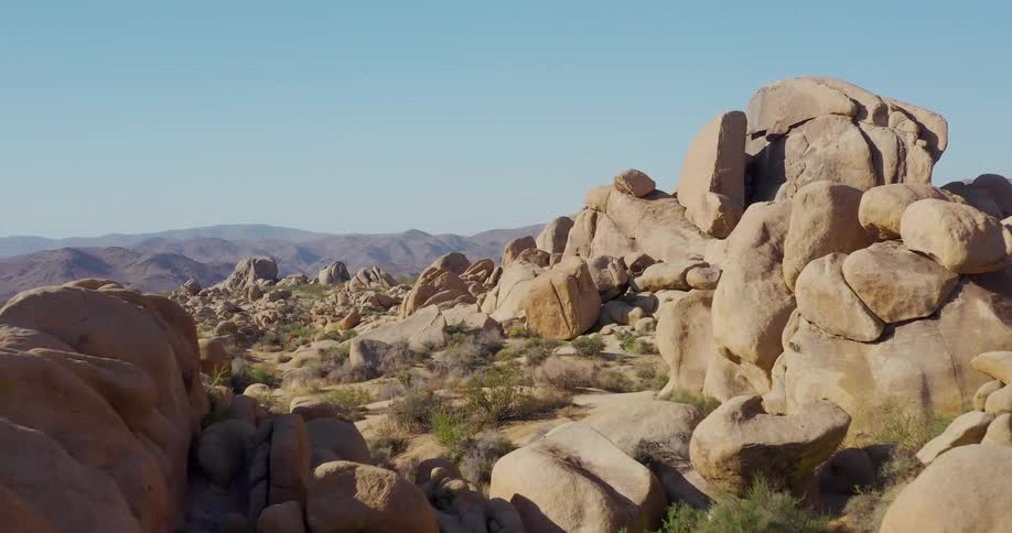 Scrub dots the terrain between large clumps of boulders while fog covers the hills in the background
