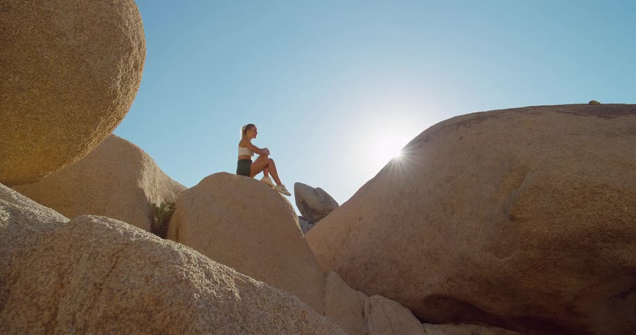 The woman looks up at the sun from the huge rocks