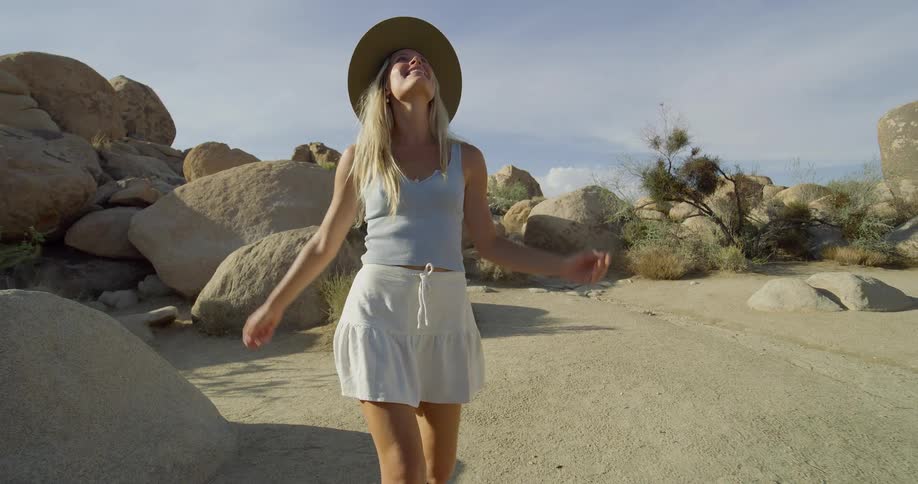 A young woman walks outdoors in a rocky desert area during daytime