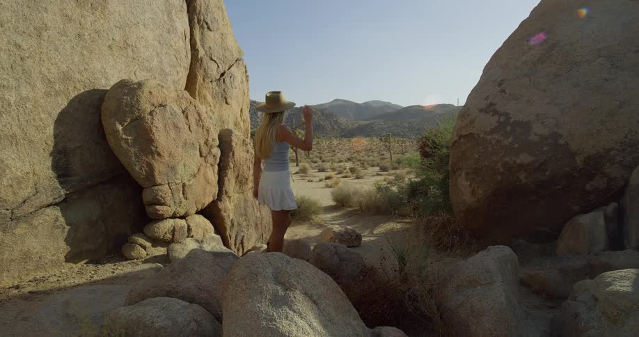 A woman steps from a boulder passage into an open desert basin