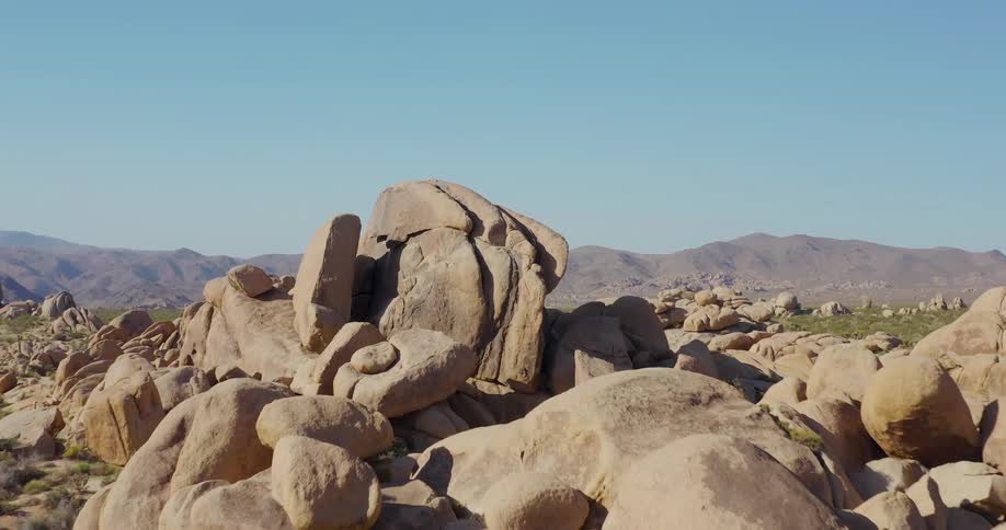 Huge boulders sit on the field before the mountains