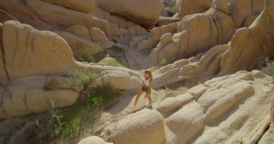 A young woman walking down a rocky mountain path at midday