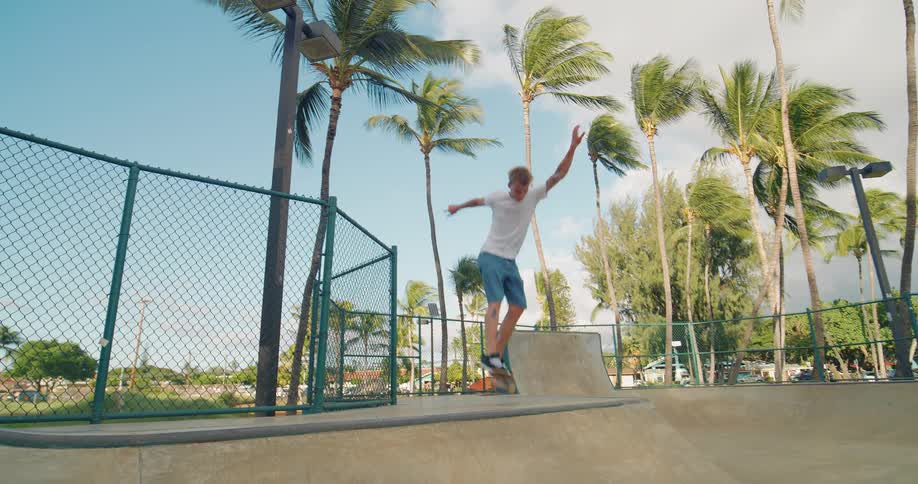 The video shows a male skateboarder at a skatepark in what appears to be a tropical location he performs a kickflip trick on a ramp flipping his board 360 degrees in the air with his feet before landing on it and riding away